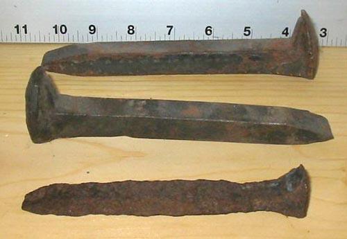 Two unused and one heavily corroded spikes. The measurement scale shown is inches