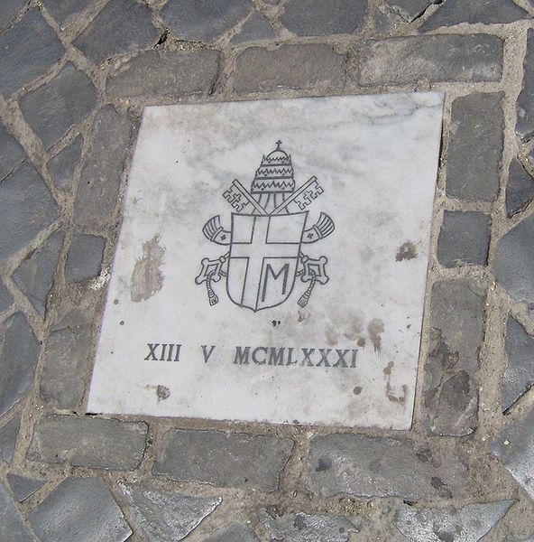 The site of the shooting is marked by a small marble tablet bearing John Paul's personal papal arms and the date in Roman numerals.