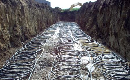 A 3-ton slinky loop prior to being covered with soil. The three slinky loops are running out horizontally with three straight lines returning the end of the slinky coil to the heat pump